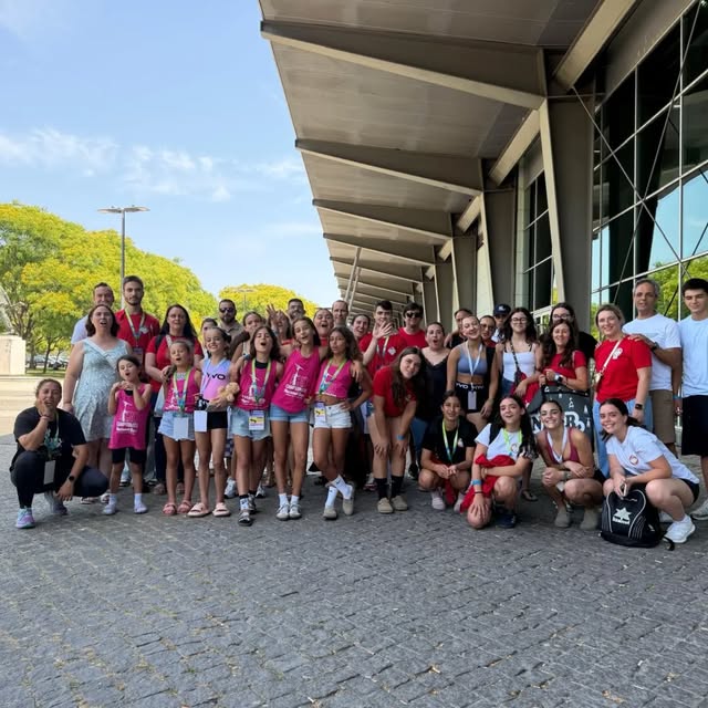 Grupo de crianças e adultos com t-shirts da casa, em dia de evento junto ao pavilhão