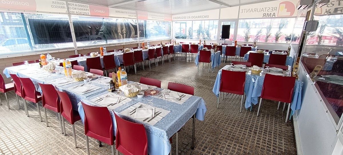 Sala do Restaurante AMR pronta, mesas postas com cadeiras vermelhas e toalhas azuis